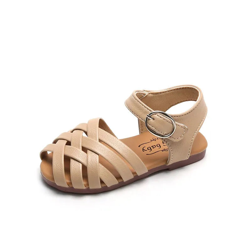 Child wearing white buckle toe soft sole woven sandals on a sunny day
