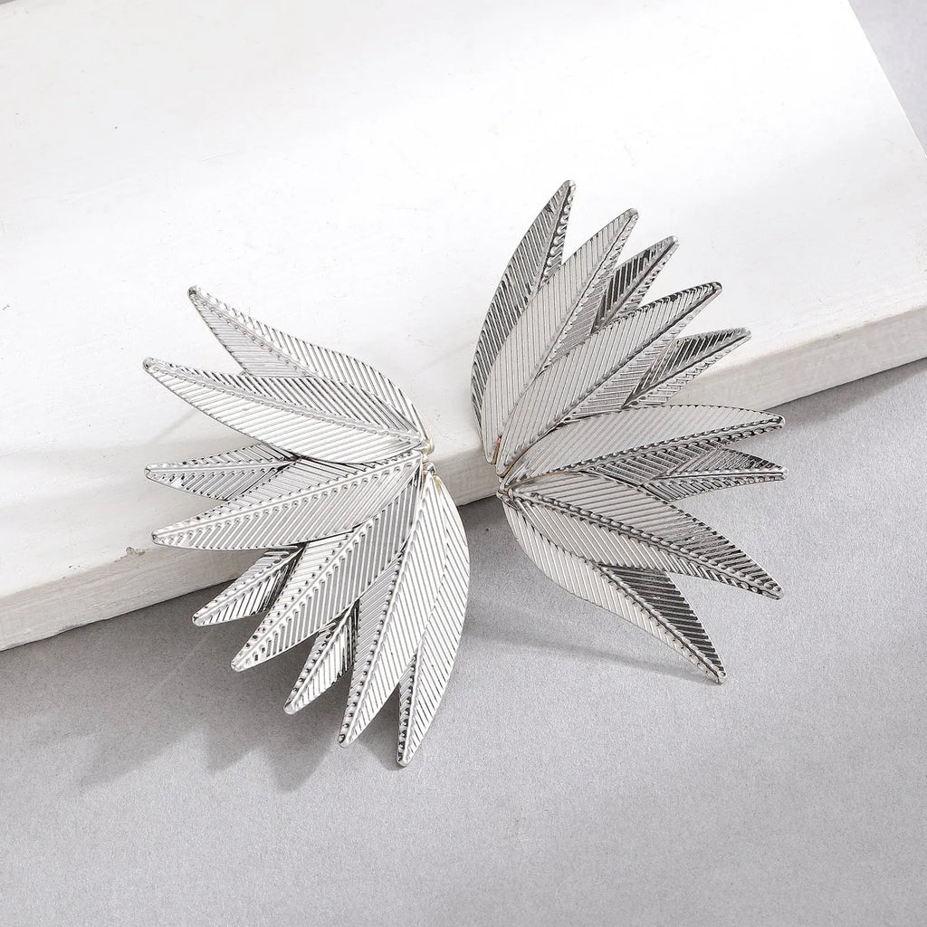 Gold and white alloy leaf shape patch earrings on a flat surface