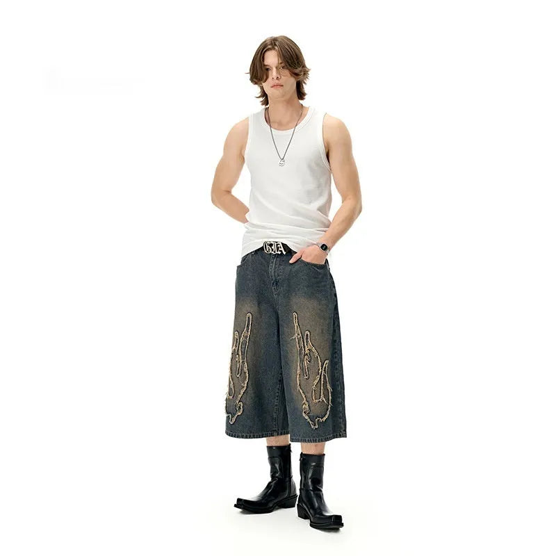 Men's black cropped denim shorts with flame embroidery patch on leg