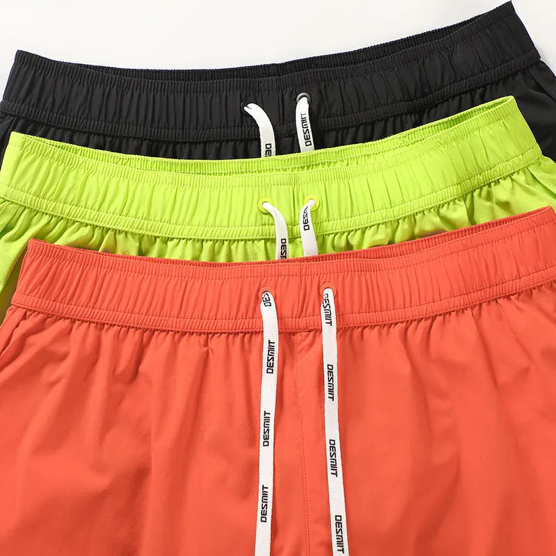 Man wearing loose orange red polyester beach shorts on sand
