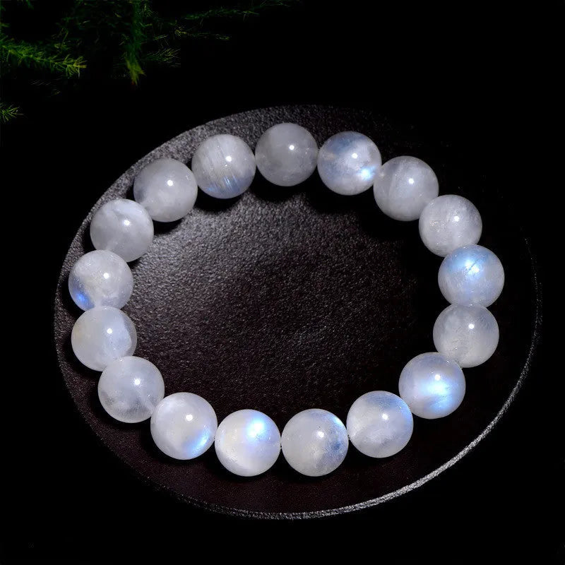 Natural white moonstone bracelet with round polished beads showing a blue sheen, laid flat.