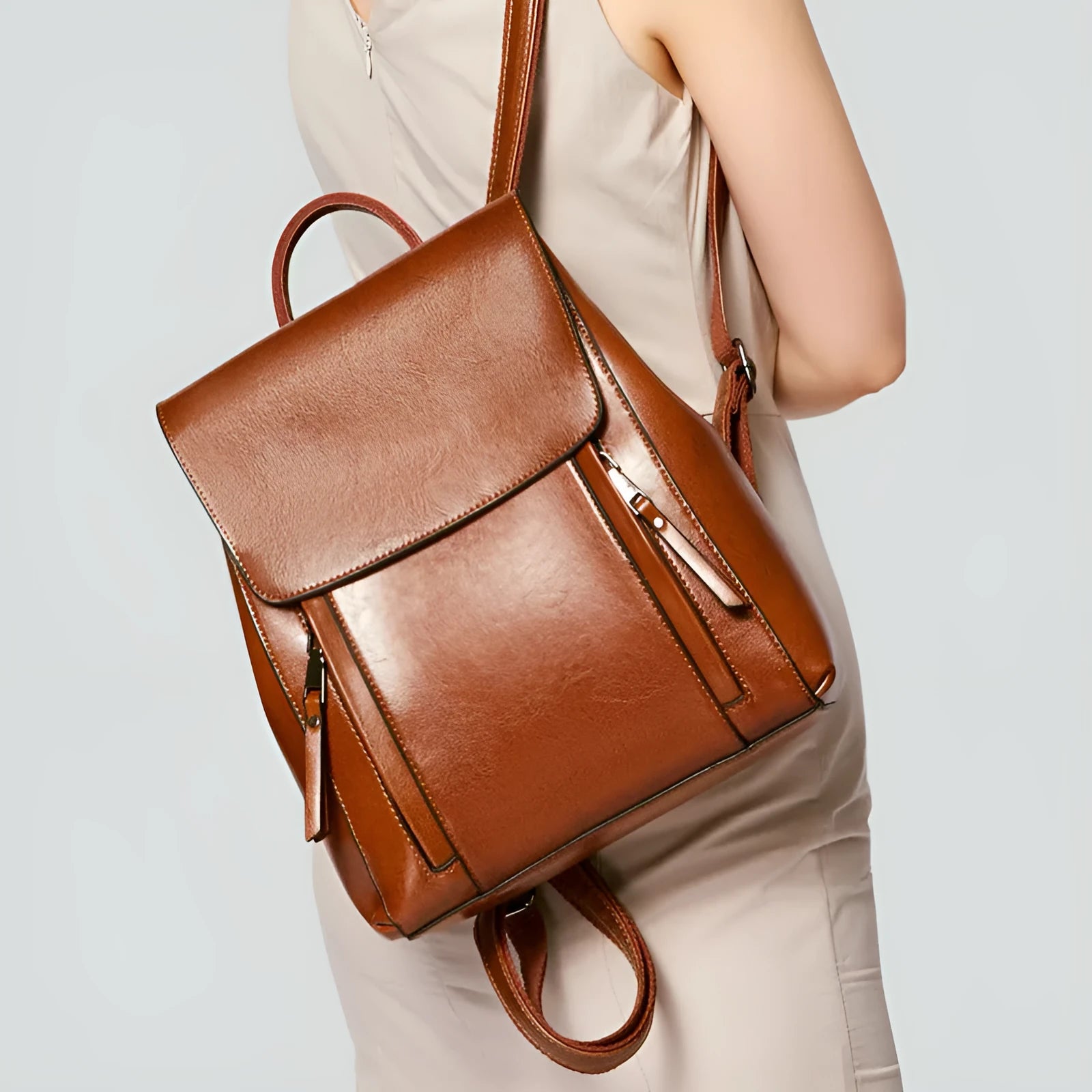 Soft black leather women's backpack with double straps, cover flap, and visible stitching, showing internal document and phone pockets.