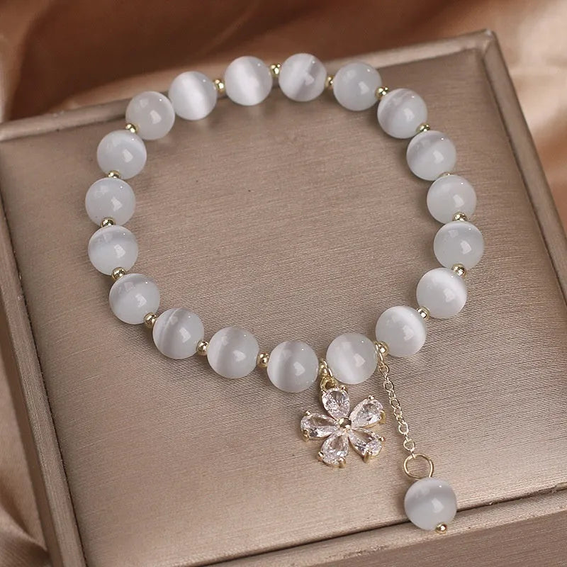 White cats eye crystal bracelet with flower charms, tassels and safety buckle closure
