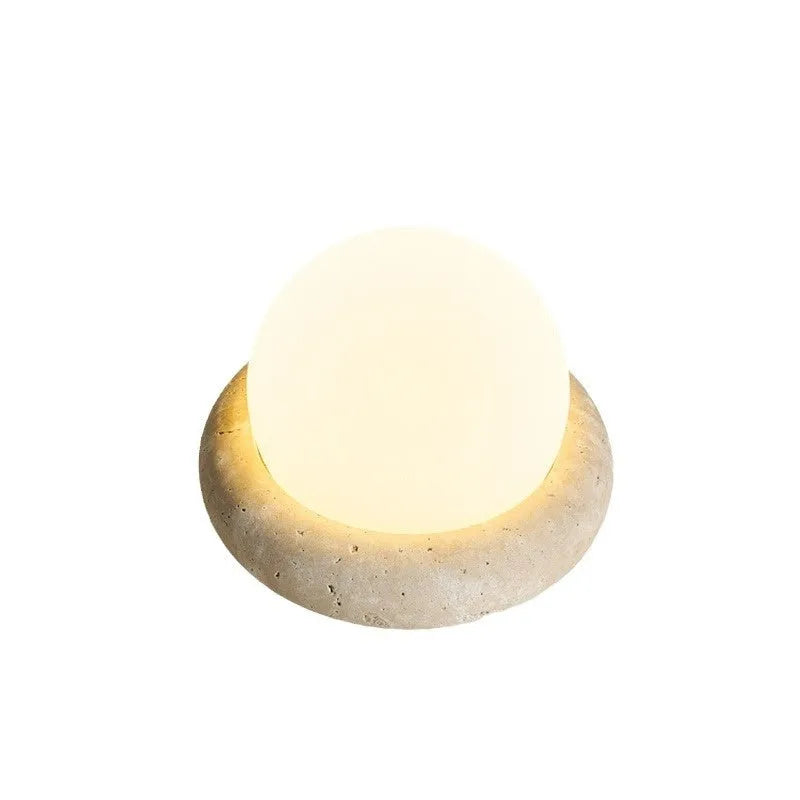 Cream coloured modern bedside night lamp with remote control on a table.