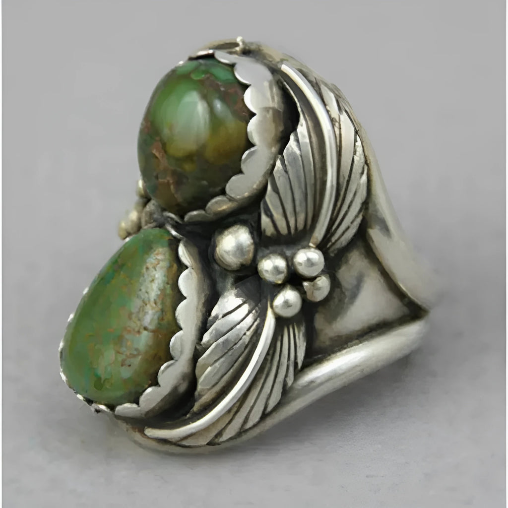 Close-up of a geometric turquoise ring with a retro inlaid design on a hand.