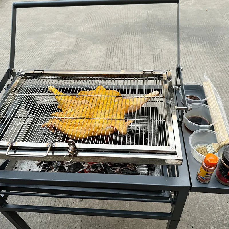 Foldable charcoal BBQ stove with a detachable grill, set up in an outdoor garden.