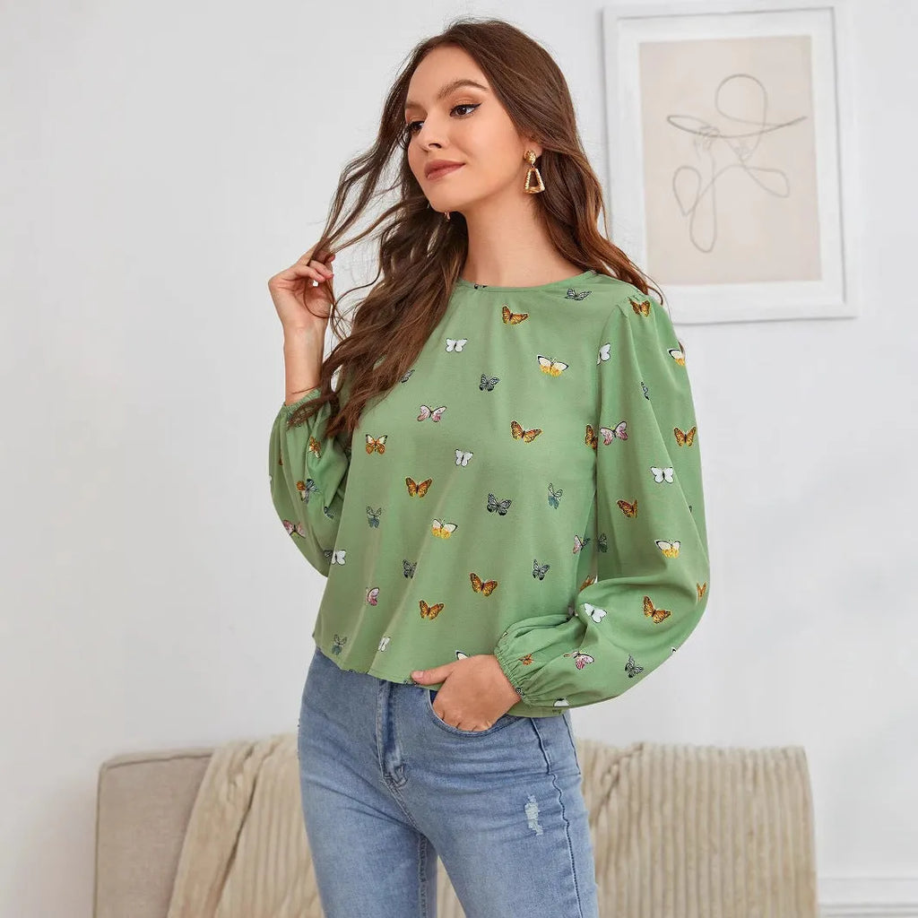 Green women's long-sleeved shirt with butterfly print, showing loose fit and long sleeves.