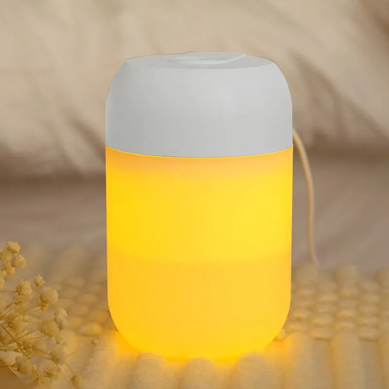 Small white cylindrical USB mini humidifier on a surface with its charging cable.