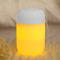 Small white cylindrical USB mini humidifier on a surface with its charging cable.