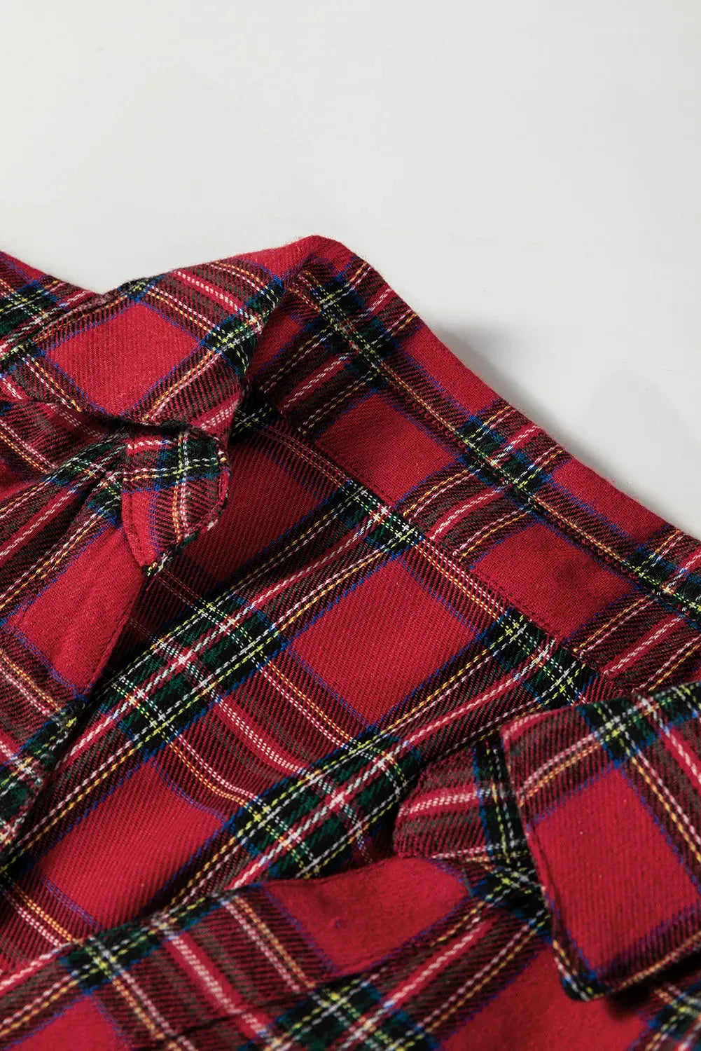 Red and black plaid mini dress with a shirt collar, long sleeves, half-button front, and a ruffled hem.