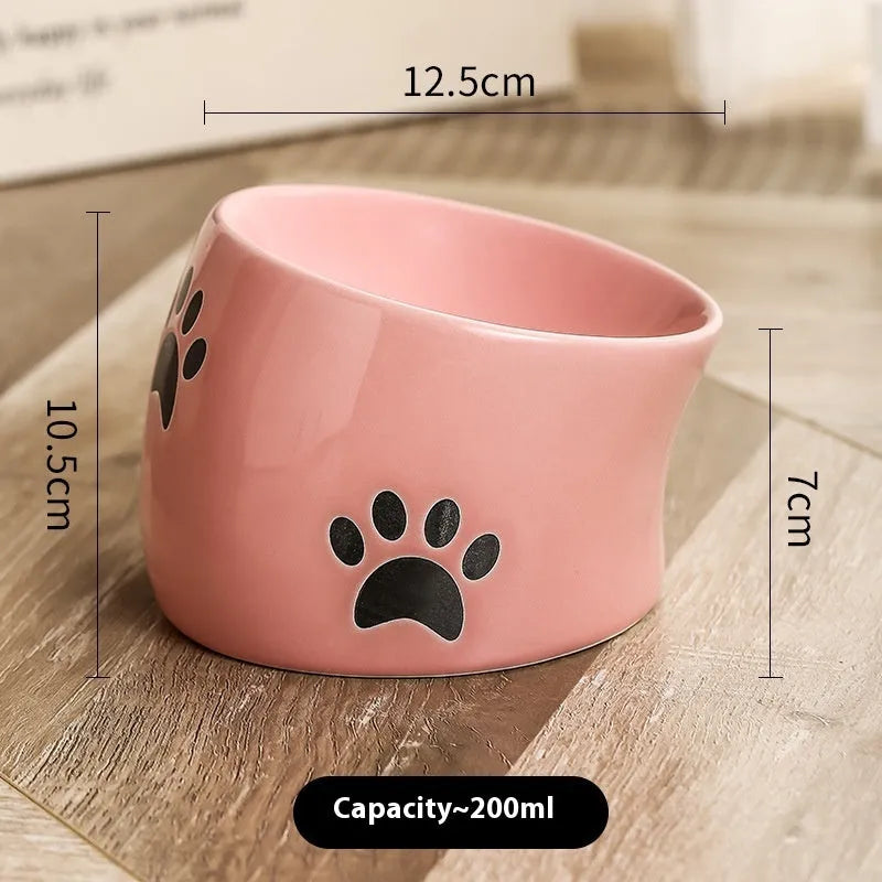 Ceramic cat food bowl with high foot base in a cat's paw print design