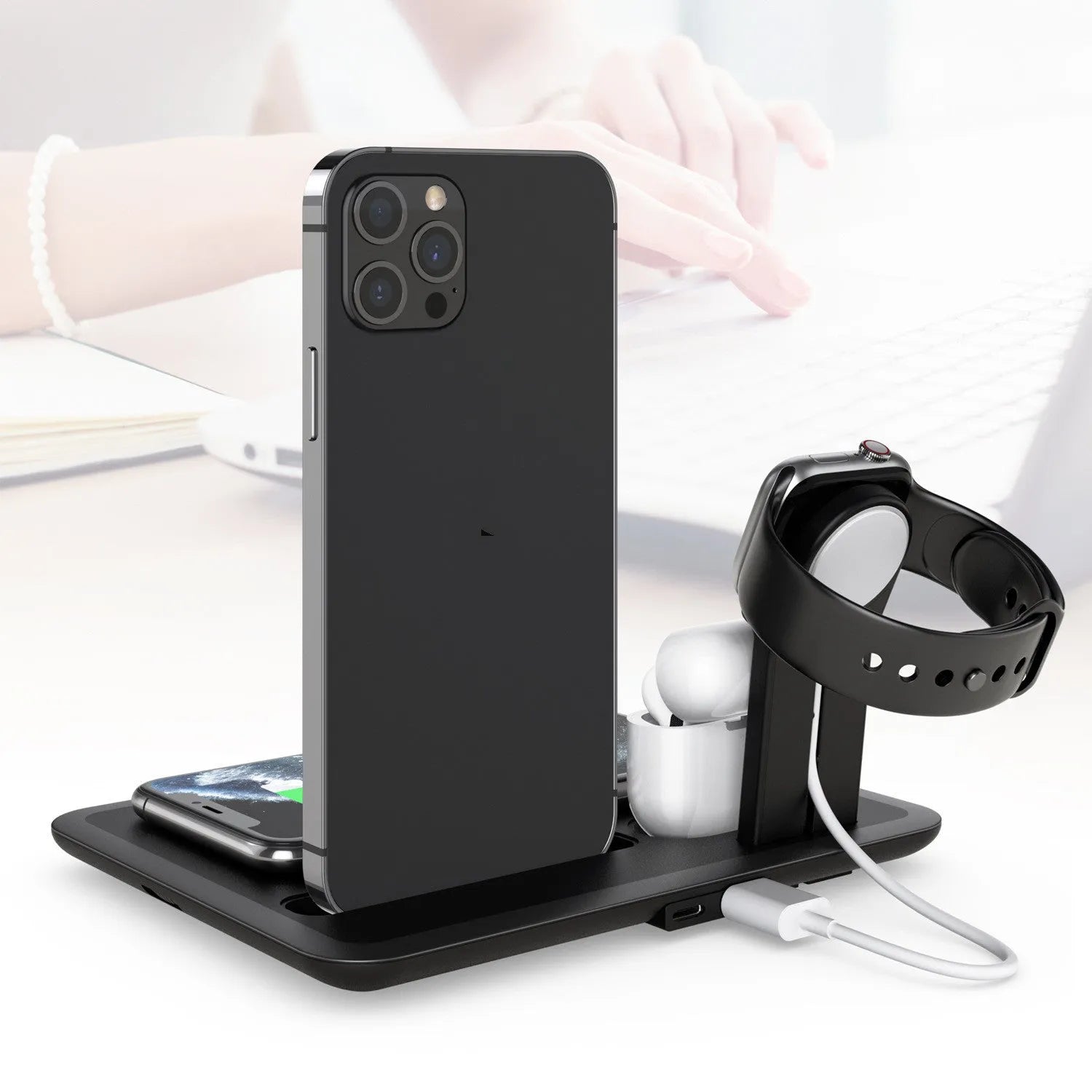 Black desktop charging hub showing wireless phone pad, USB port, watch port, and headphone charging dock.