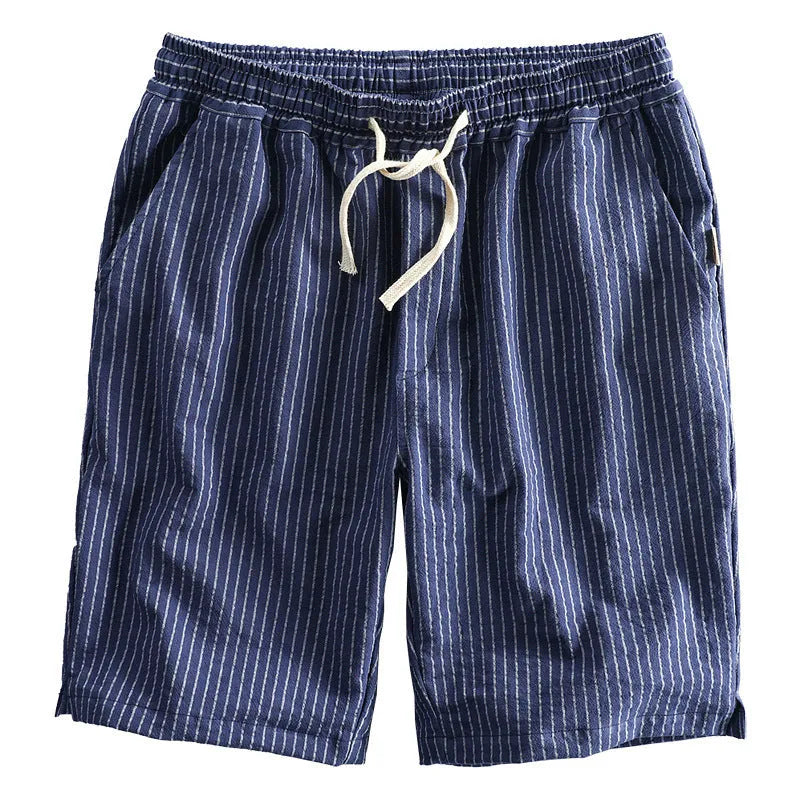 Man wearing loose straight-leg striped cotton shorts in a light colour, showing the mid waist and casual fit.