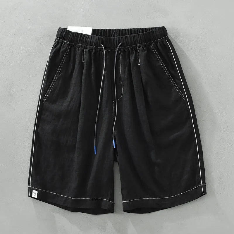 Man wearing loose straight-leg linen shorts in green, showcasing mid-waist and drawstring detail.
