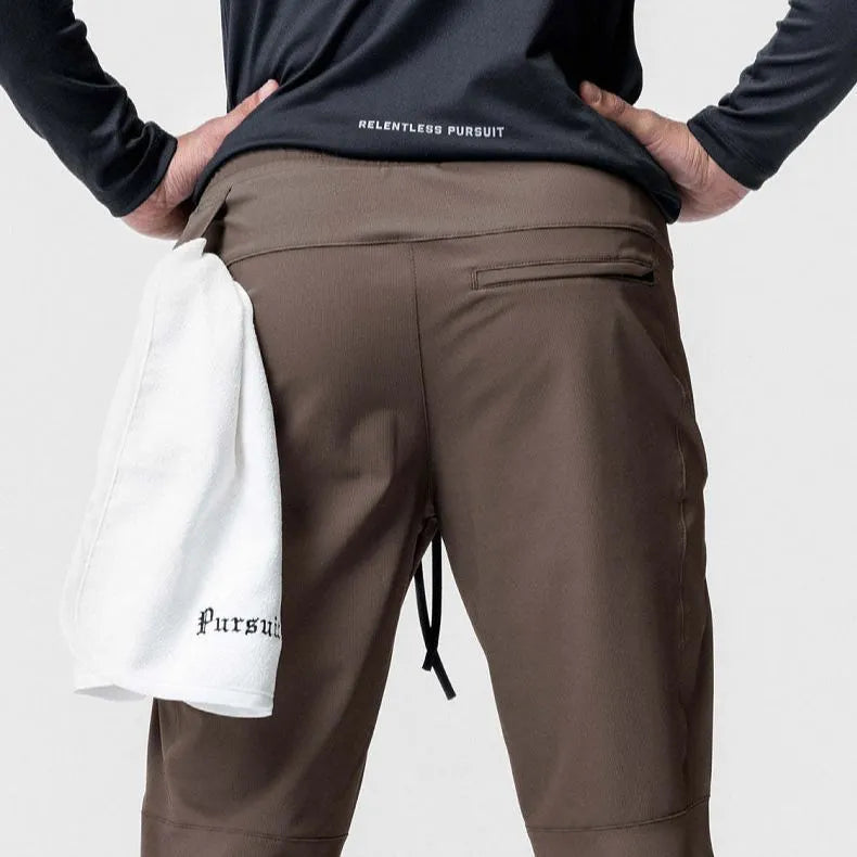 Man wearing dark grey tapered fitness trousers with adjustable ankle ties during a workout.