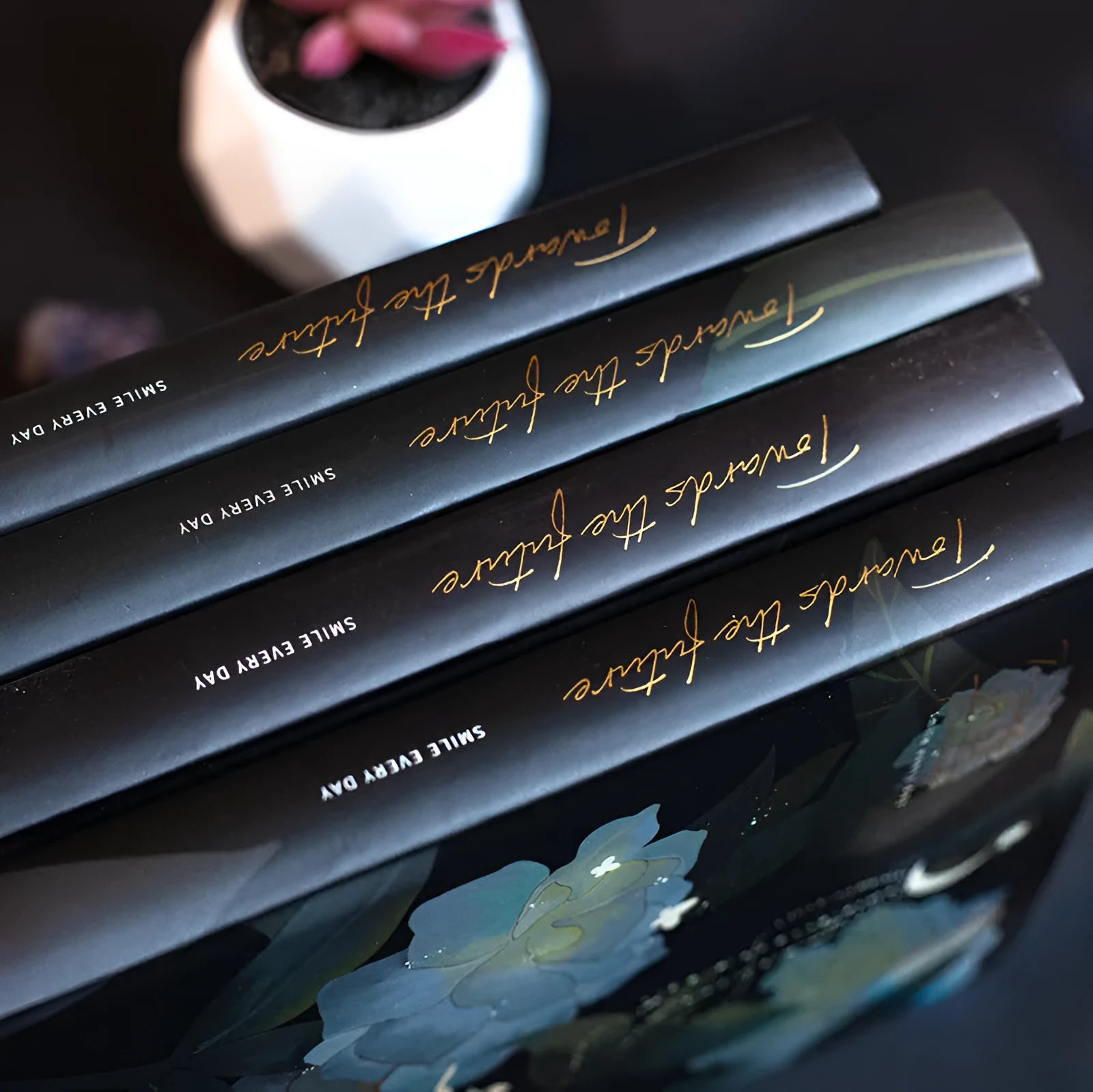 A5 notebook with a luminous cover shown in deep blue, open to reveal pages with colour illustrations.