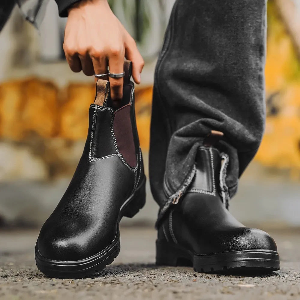 Vintage brown unisex Chelsea boot with round toe and beef tendon sole on a wooden floor.