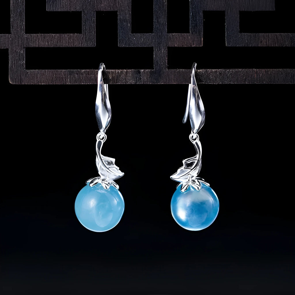 A pair of vintage-style silver earrings featuring aquamarine leaf and four-petal flower designs.
