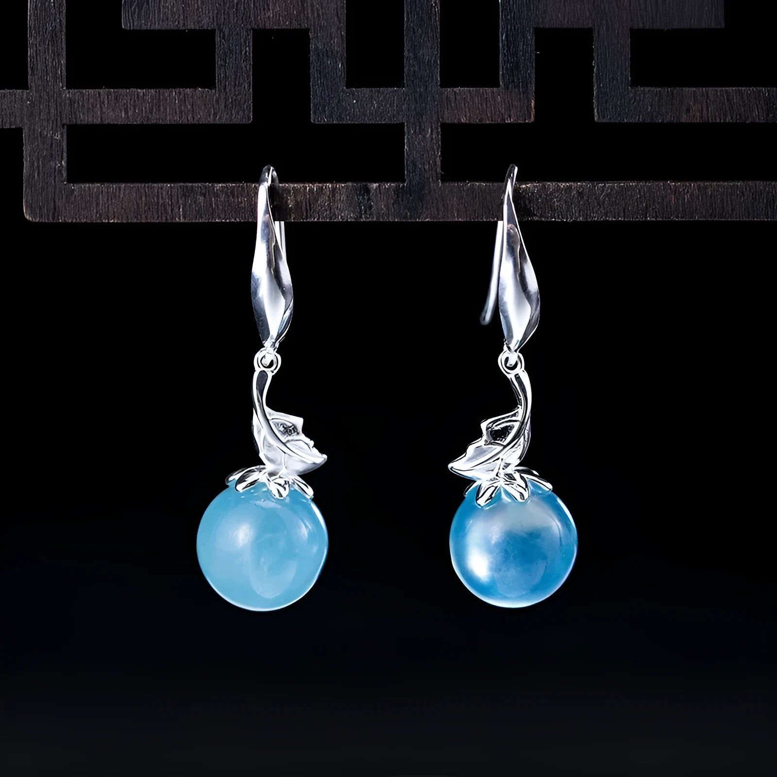 A pair of vintage-style silver earrings featuring aquamarine leaf and four-petal flower designs.