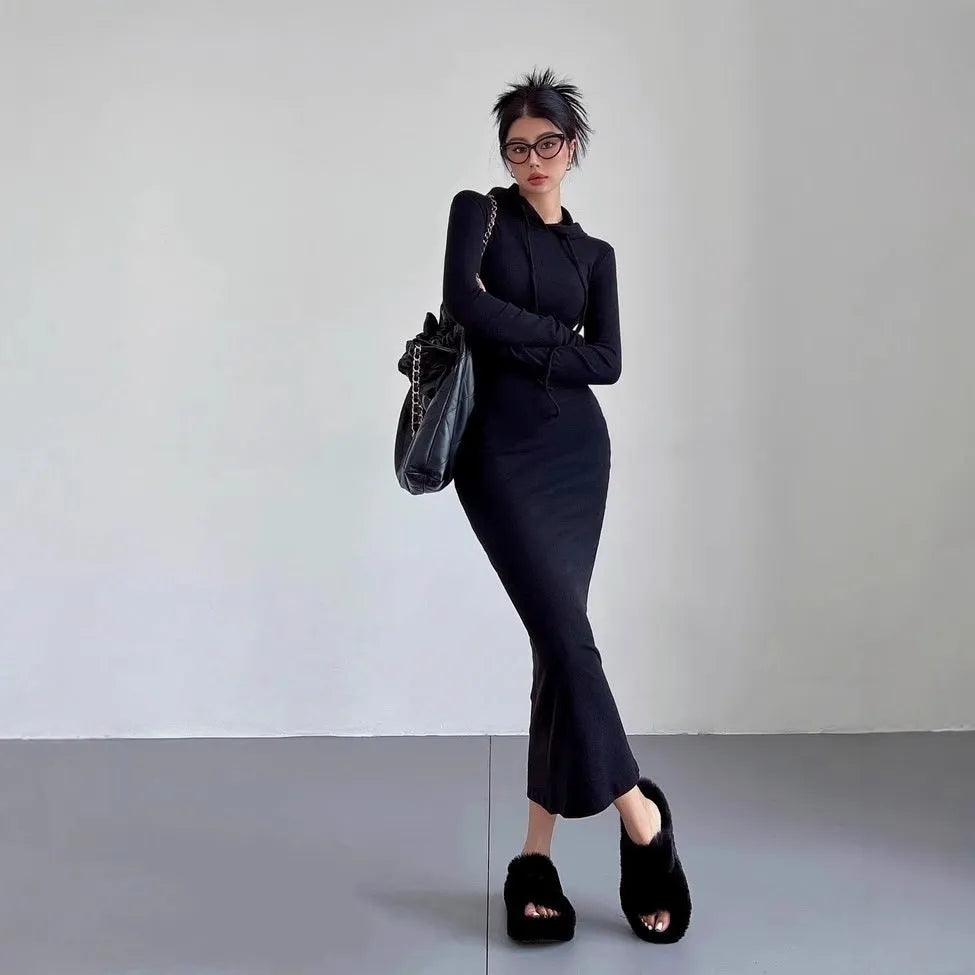 A woman modelling a grey hooded long-sleeve sheath dress with a high waist and over-the-knee length.