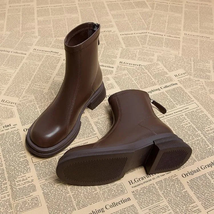 Women's black flat-heel ankle boots with round toe and back zipper.