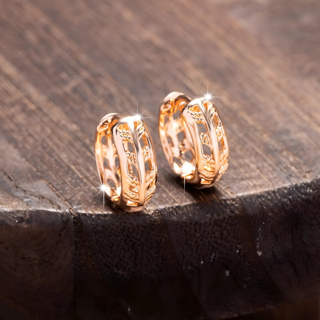 Rose gold hollowed-out heart and leaf shaped copper earrings on a white background, showing intricate cut-out details.