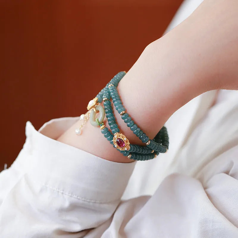 Women's bracelet with small blue water jade abacus beads, tourmaline rings, and pearls on a wrist