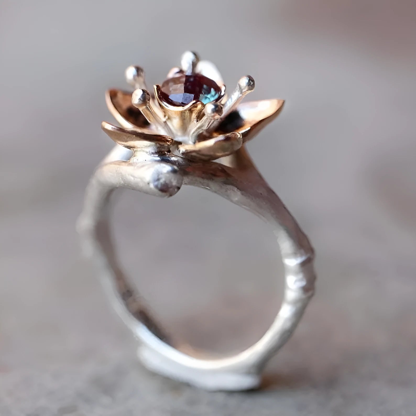 A silver two-tone floral ring with a geometric shape on a model's finger.