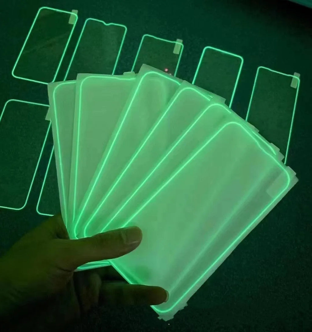 Fluorescent tempered glass screen protector glowing on an iPhone 13, showing pink luminous edge and precise camera cutout.