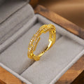 Gold coloured geometric open fashion ring on a plain background.