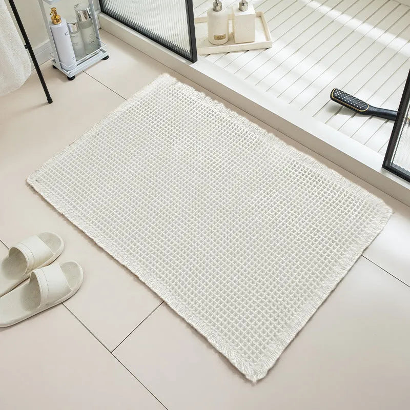 A beige checkered non-slip polyester bathroom carpet on a tiled floor.