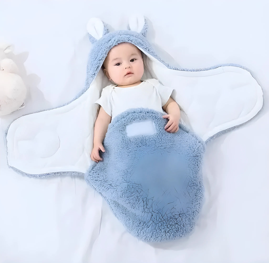 Baby wearing a grey adjustable fleece swaddle sleep sack with velcro wings