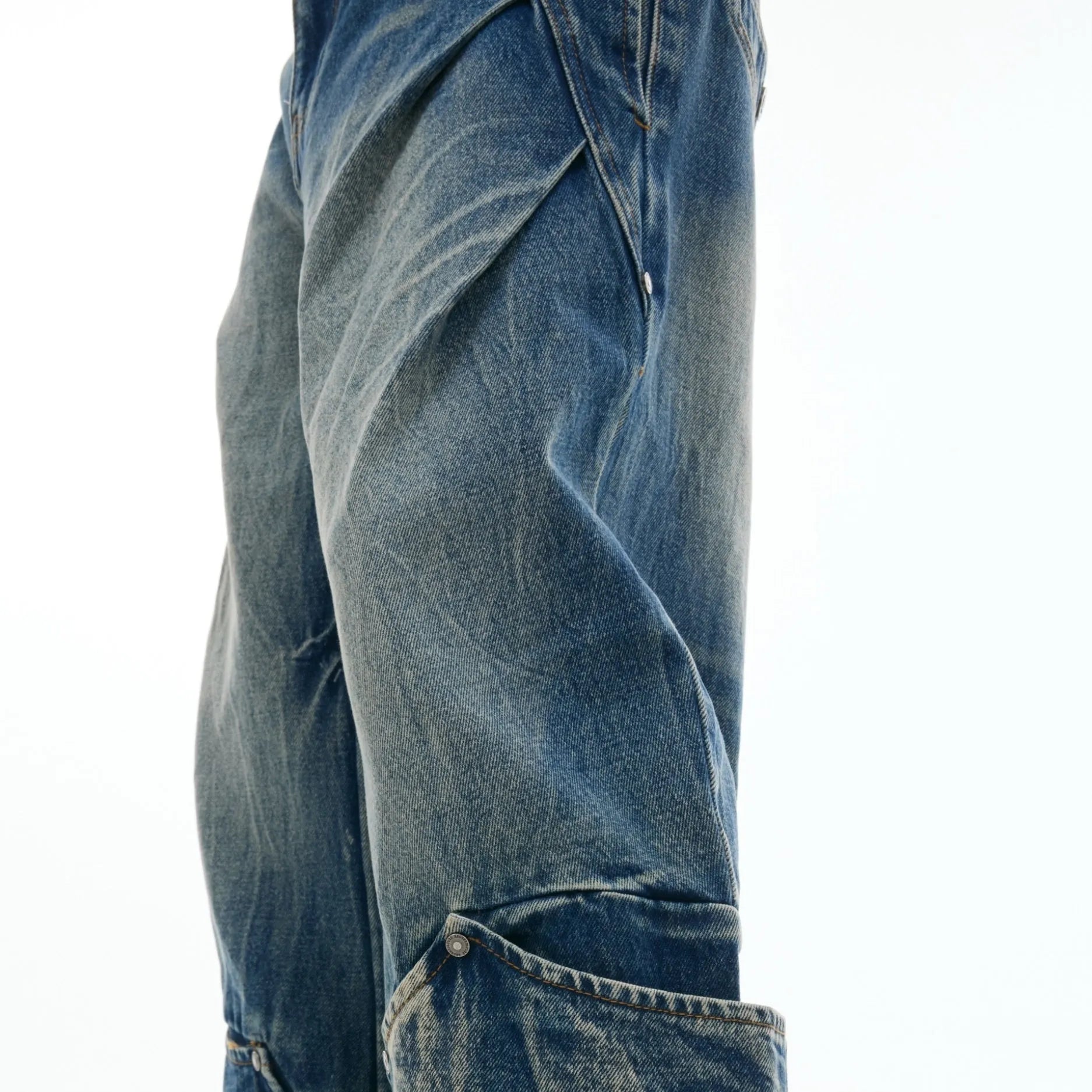 Men's verdant blue loose fit jeans showing curved knife pattern detail and vintage wash on a cotton blend fabric.