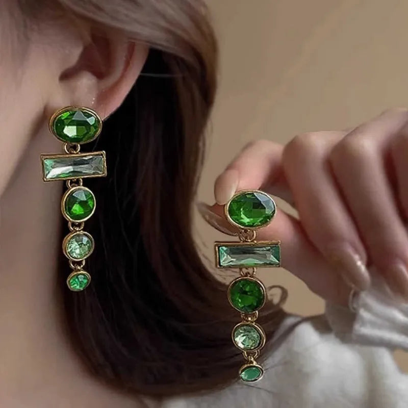 Green gradient tassel drop earrings with geometric alloy shapes and inlaid zircon stones on a white background.