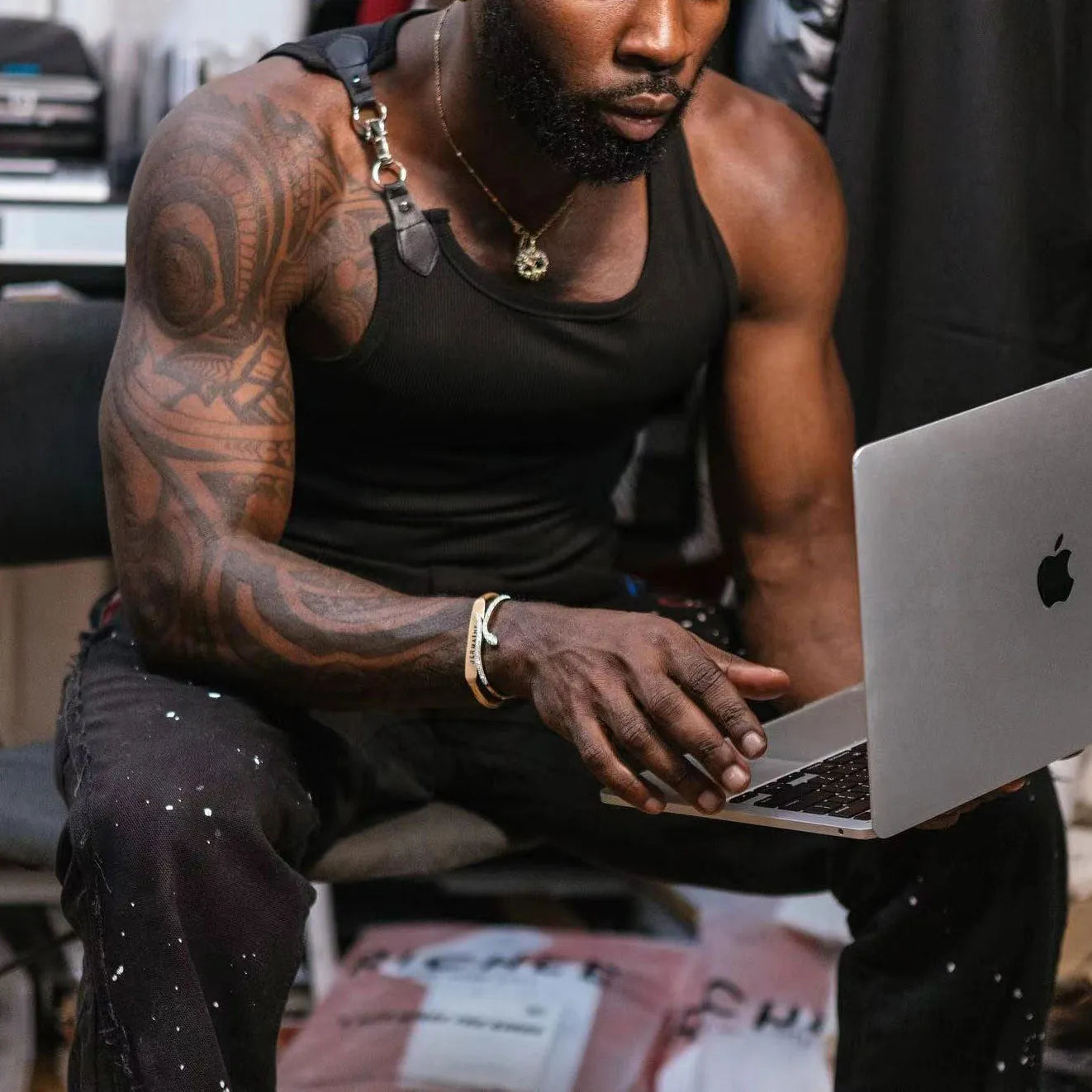Plain black sleeveless tight-fitting vest on a hanger.