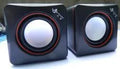 Small square black USB-powered 2.0 desktop computer speaker on a desk.