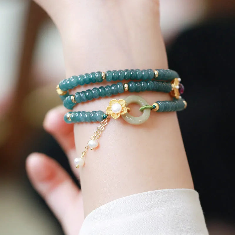 Women's bracelet with small blue water jade abacus beads, tourmaline rings, and pearls on a wrist