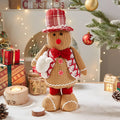 Gingerbread man cloth Christmas ornament with red and white hat, hanging on tree branch
