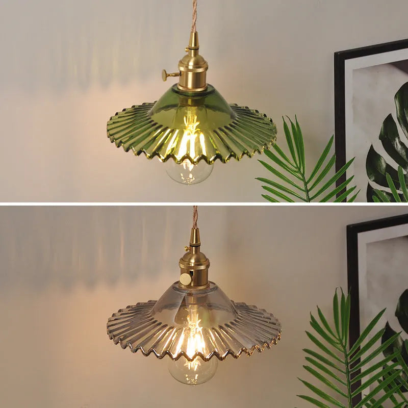 Retro brass lotus wall lamp with a 22cm green glass shade mounted on a copper base beside a bed.