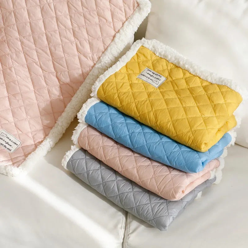 Quilted blue cloth pet blanket for cats, shown on a pet bed.