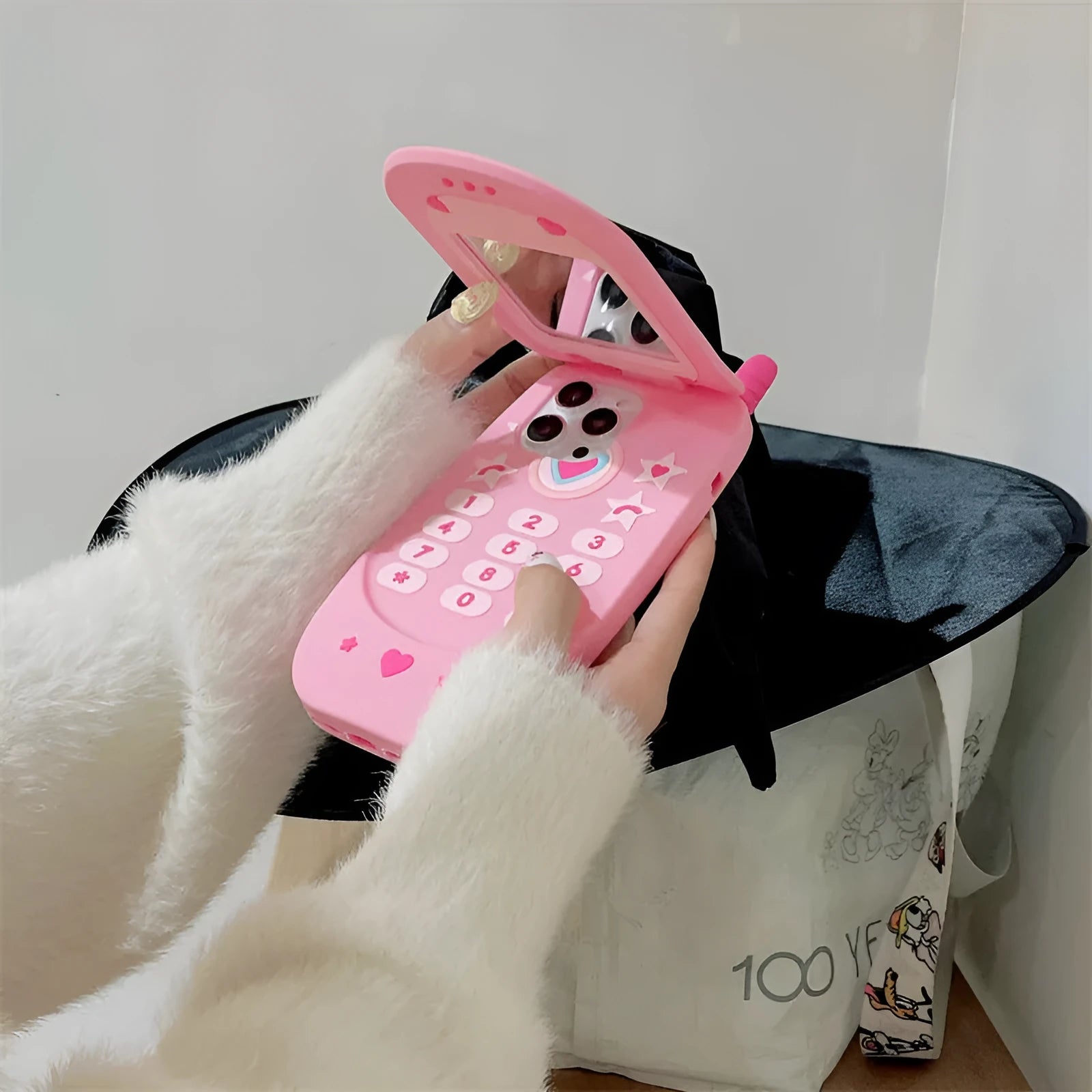 Light pink silicone flip phone case with built-in mirror for iPhone on a table