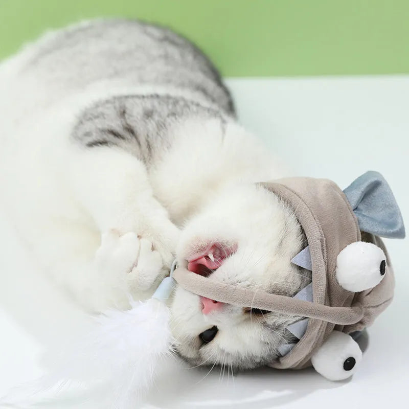 Grey dinosaur-themed head-mounted cat toy with feathers and big eye fish design on adjustable band
