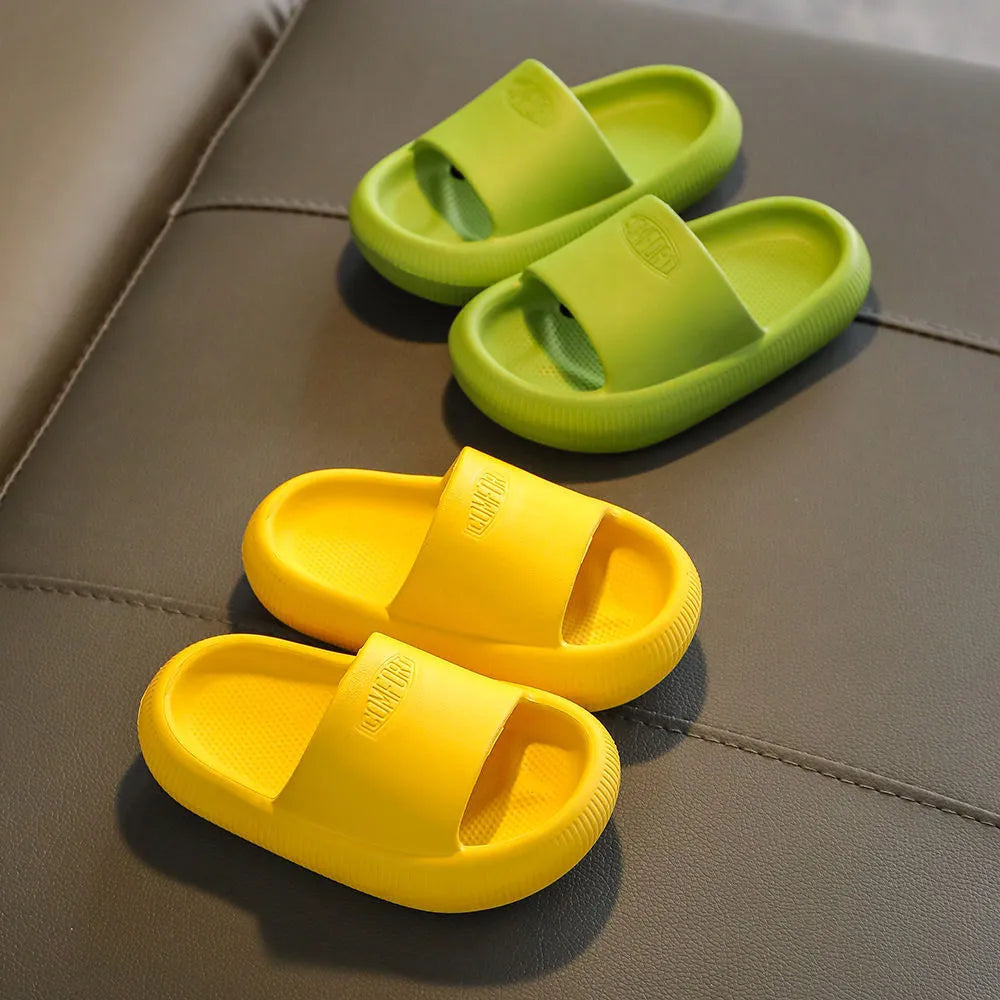 Bright coloured EVA children's house slippers with thick, textured non-slip soles on a wooden floor.