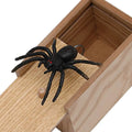 Wooden prank scare box with a lifelike spider figurine on a table.