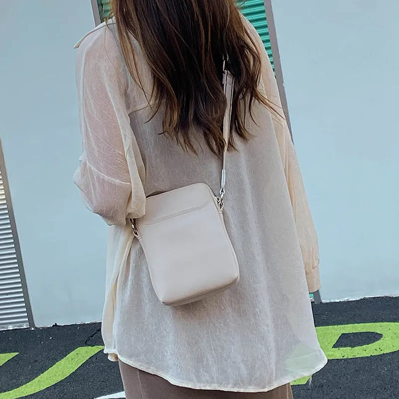 Solid colour small PU crossbody shoulder bag for mobile phones on a strap.
