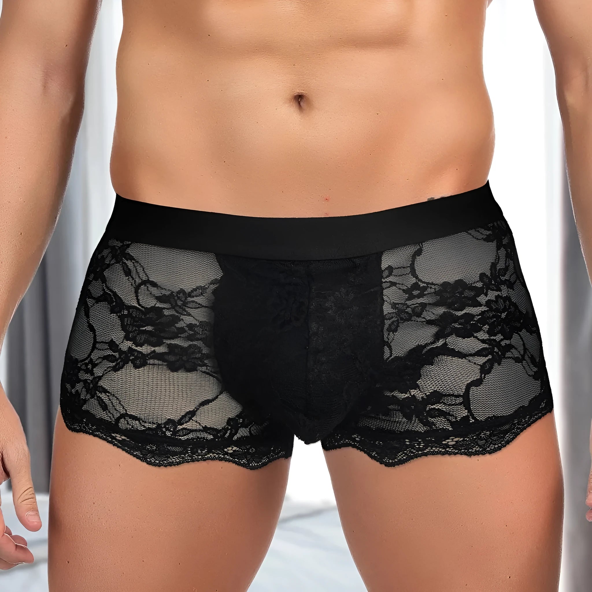 Men's black lace briefs with hollow-out see-through panels on a grey background.