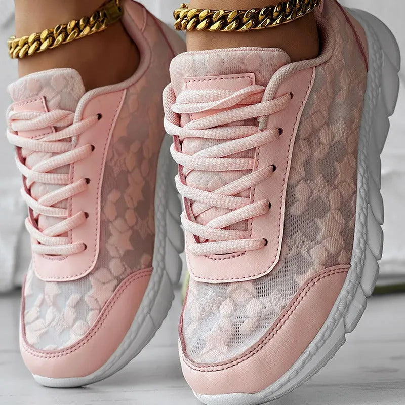 Women's white canvas sports shoes with a flat heel and round toe on a plain background.