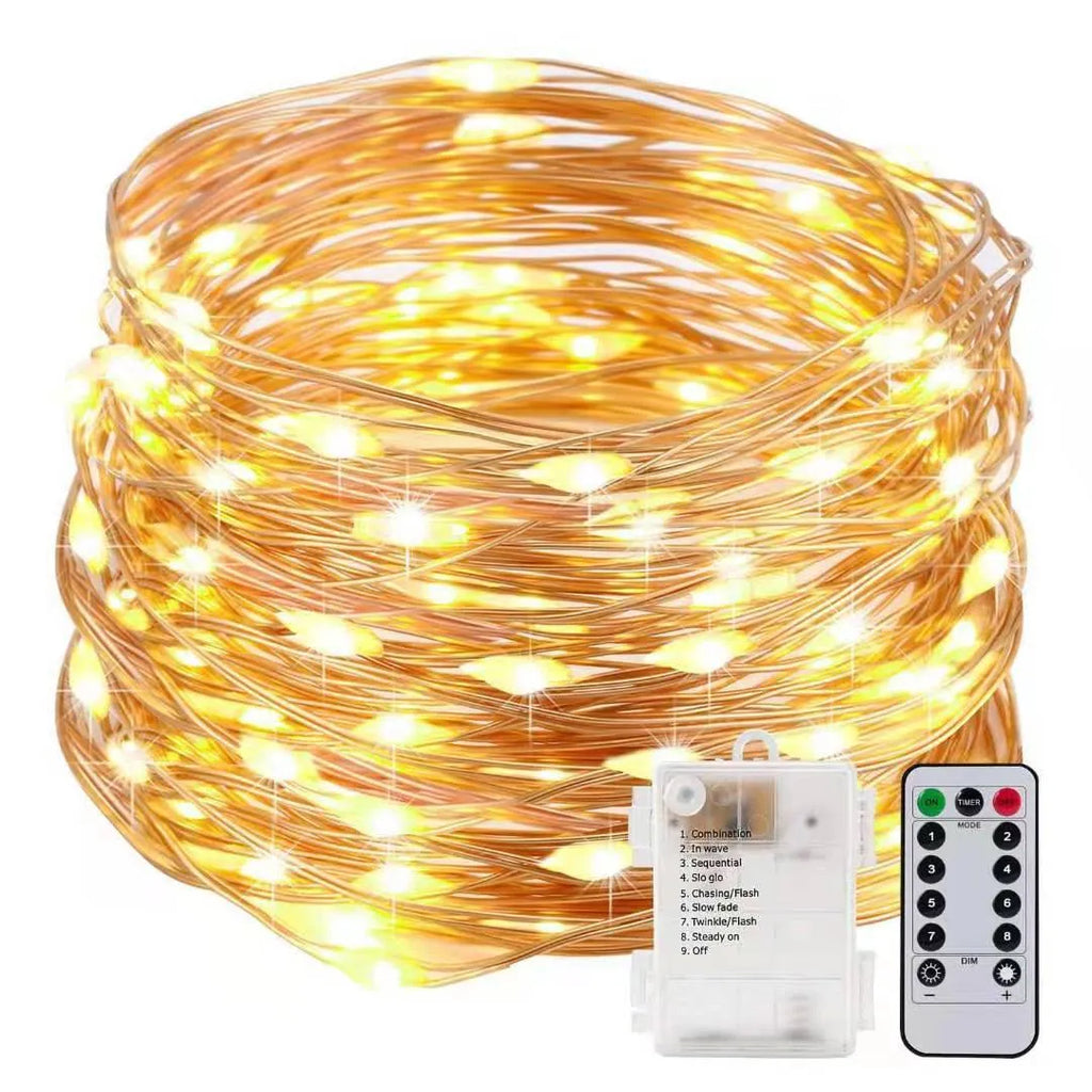 Copper wire fairy lights wrapped around a jar, showing warm white LEDs and a small battery box on a wooden table.