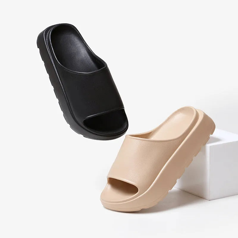 Women's beige fish mouth slippers with a thick light-coloured sole on a wooden floor.