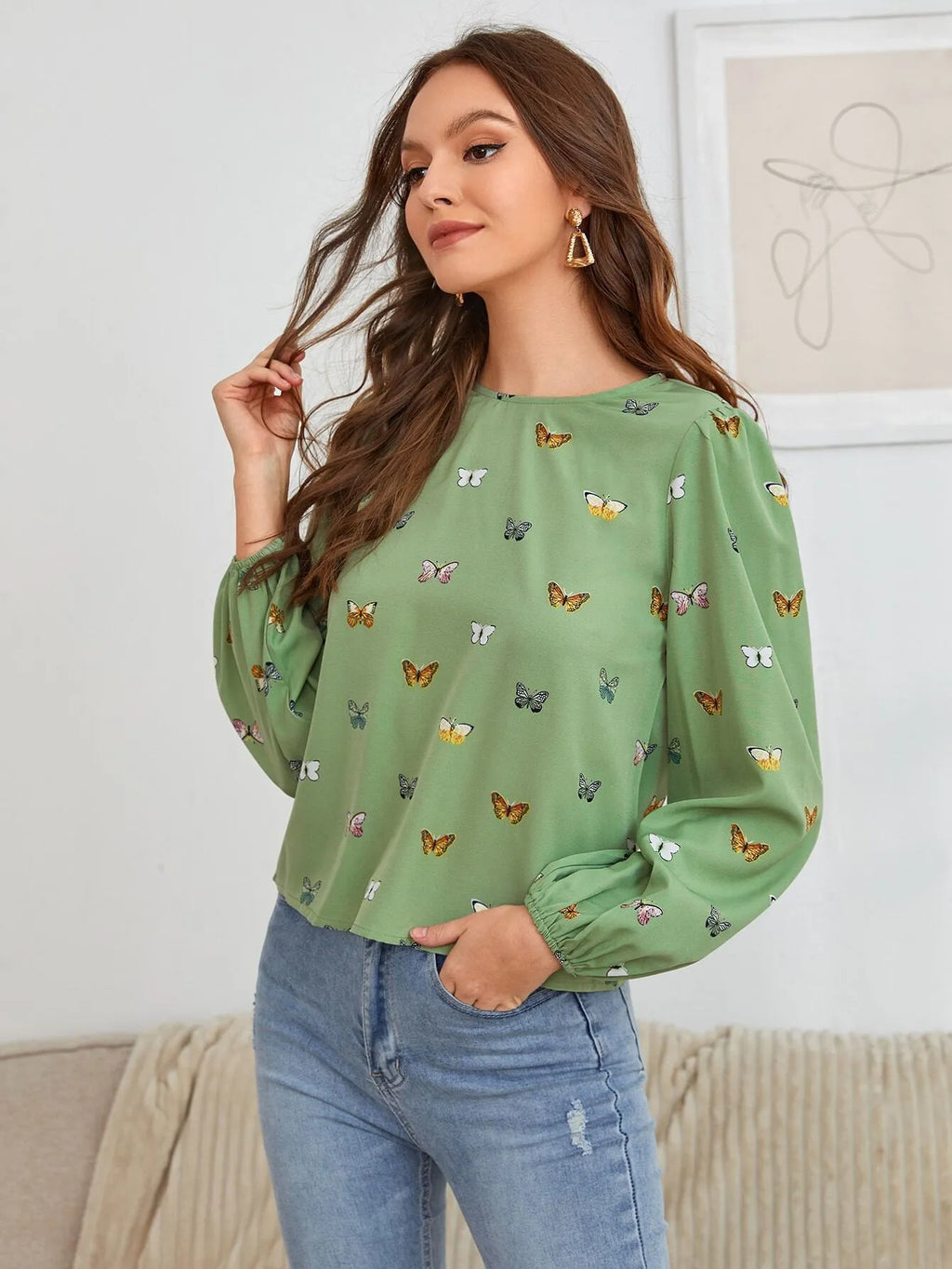 Green women's long-sleeved shirt with butterfly print, showing loose fit and long sleeves.